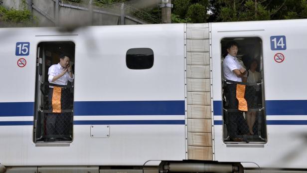 Zwei Männer stehen in den offenen Türen eines japanischen Hochgeschwindigkeitszuges.