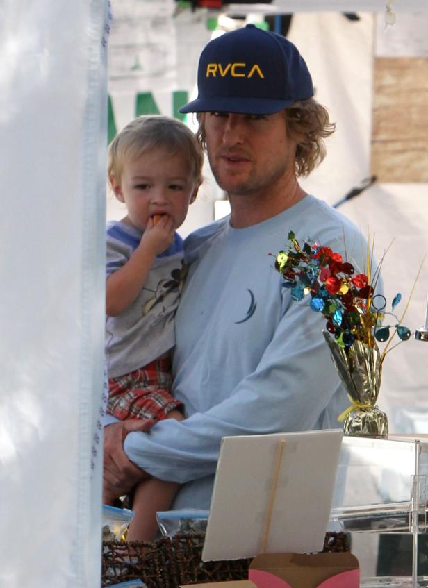 Owen Wilson trägt sein Kind, das einen Snack isst.