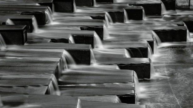 Ein gestuftes Wasserspiel mit kleinen Wasserfällen in Schwarzweiß.