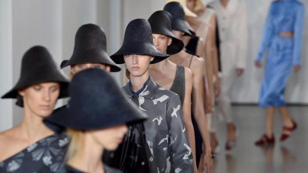 Models präsentieren Hüte und Kleidung auf einem Laufsteg.