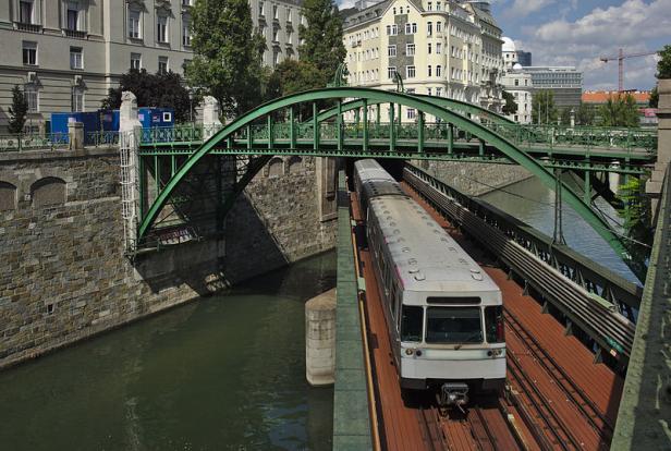 Eine U-Bahn fährt auf einer Brücke über einen Kanal in Wien.