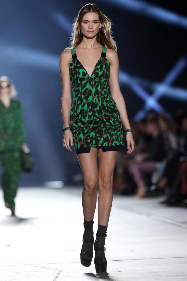 Eine Frau in einem grünen Kleid mit Tiermuster auf einem Laufsteg.