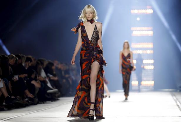 Eine blonde Frau in einem gemusterten Kleid auf einem Laufsteg.