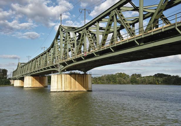 Eine grüne Stahlbrücke überspannt einen Fluss.