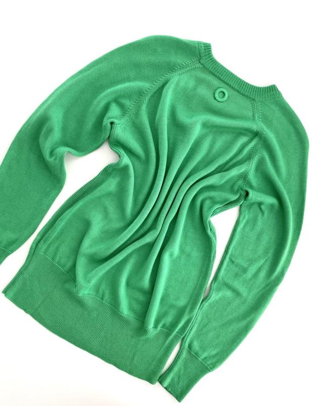 Ein grüner Strickpullover liegt auf einem weißen Hintergrund.
