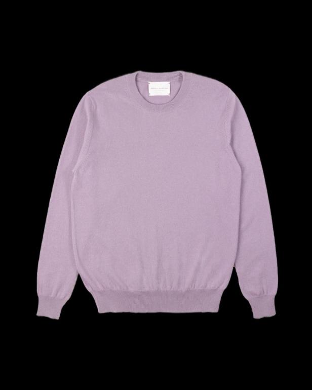 Ein helllila Kaschmirpullover liegt auf einem schwarzen Hintergrund.
