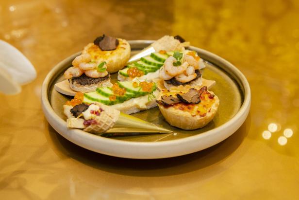 Eine Auswahl an Canapés mit Garnelen, Kaviar, Gurken und Trüffeln auf einem Teller.