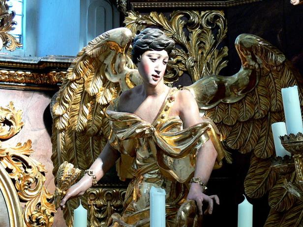 Eine goldene Engelsstatue mit ausgebreiteten Flügeln und Kerzen.