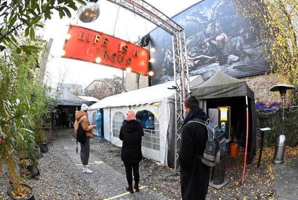 Menschen stehen vor Zelten unter einem Schild mit der Aufschrift „Life is a Circus“.
