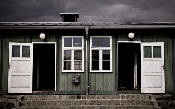 Ein grünes Gebäude mit weißen Türen und Fenstern unter einem dunklen Himmel.
