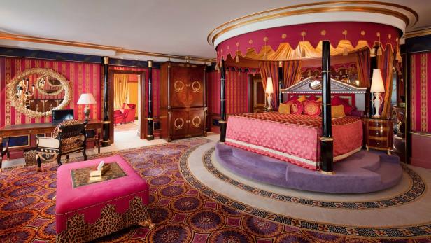 Ein opulent eingerichtetes Schlafzimmer mit Himmelbett und auffälligem Teppich.