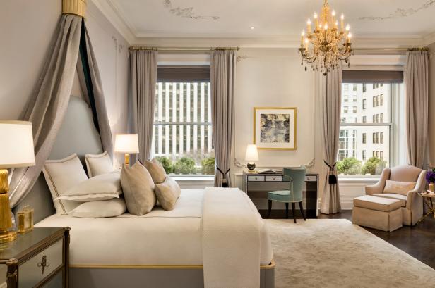 Ein luxuriöses Schlafzimmer mit Himmelbett, Schreibtisch und großem Fenster.