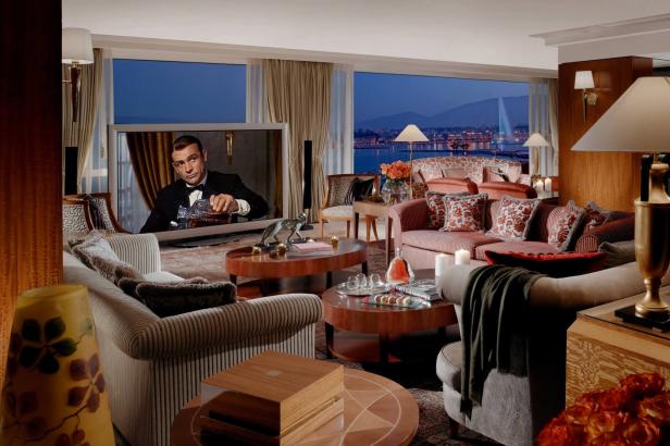 Ein luxuriöses Wohnzimmer mit Blick auf eine Stadt bei Nacht und einem Fernseher, auf dem Sean Connery zu sehen ist.