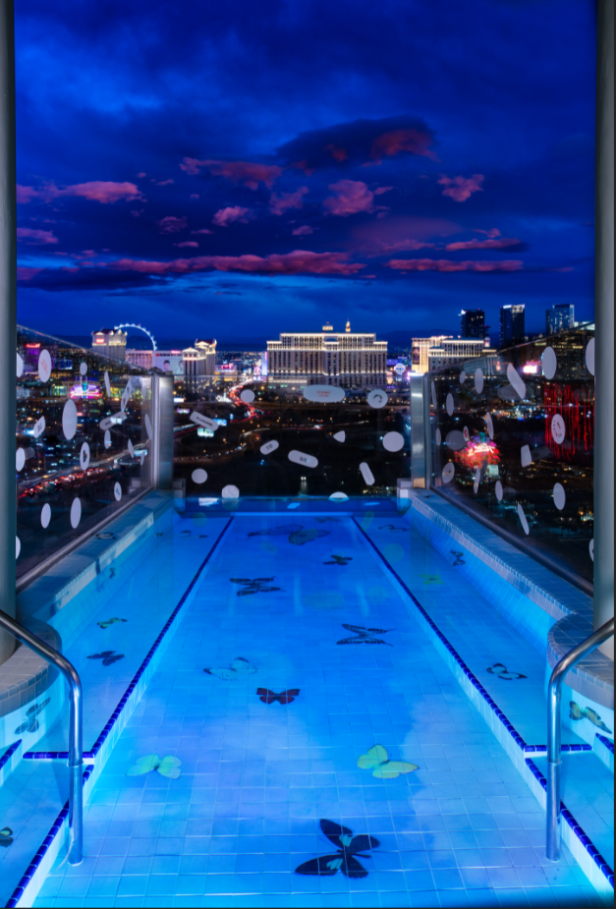 Ein Schwimmbad auf einem Dach mit Blick auf die Skyline von Las Vegas bei Nacht.