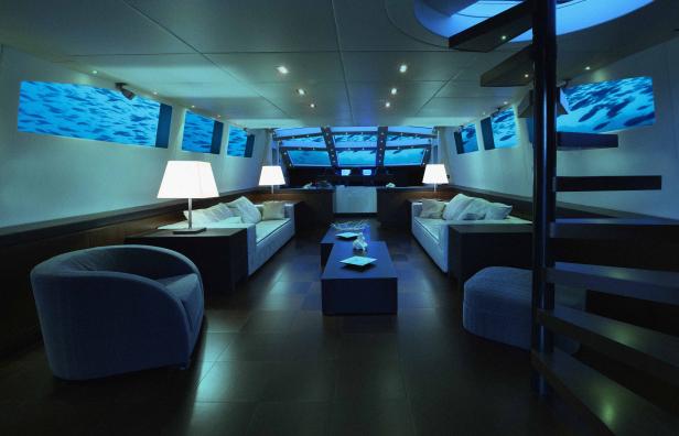 Ein luxuriöser Yacht-Innenraum mit Unterwasserblickfenstern und blauer Beleuchtung.