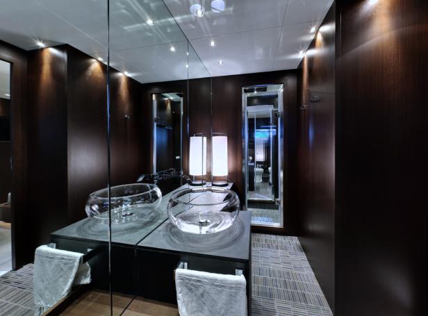 Ein Badezimmer mit zwei Glaswaschbecken und dunklen Holzvertäfelungen.