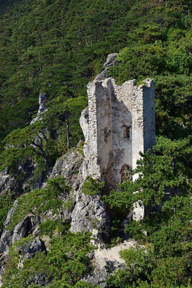 Die Ruine einer mittelalterlichen Burg thront auf einem felsigen Hügel.