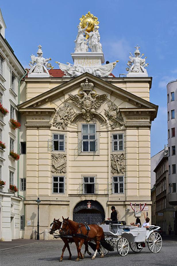 Eine Pferdekutsche fährt vor dem Schweizer Tor der Hofburg in Wien.