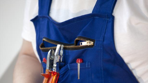 Eine blaue Latzhose mit Werkzeugen in den Taschen.