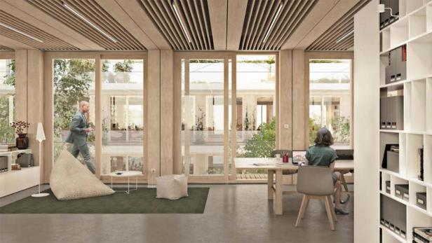 Ein Mann betritt ein helles Büro, während eine Frau an einem Schreibtisch arbeitet.