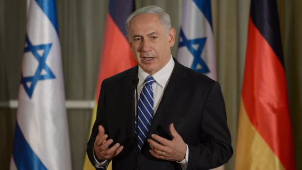 Benjamin Netanjahu spricht vor israelischen und deutschen Flaggen.