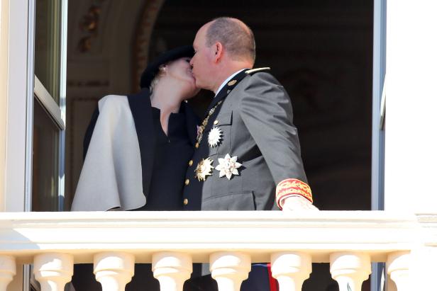Fürst Albert und Charlène von Monaco küssen sich auf einem Balkon.