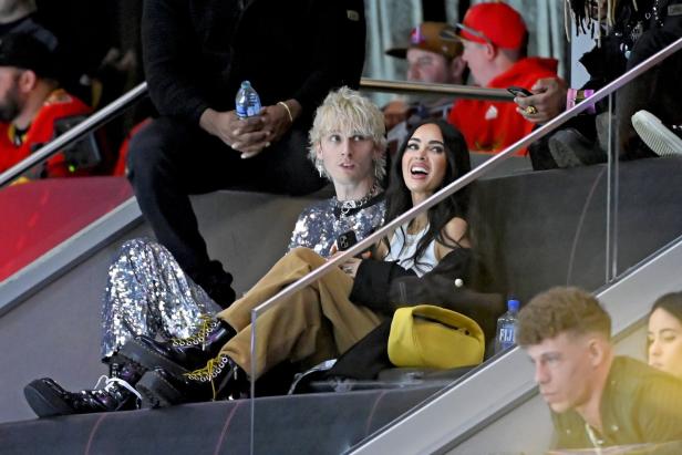 Machine Gun Kelly und Megan Fox sitzen bei einer Veranstaltung auf der Tribüne.