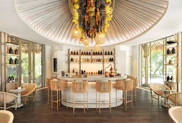 Eine Bar mit Rattanstühlen und einer Dekoration aus getrockneten Blumen unter einer Holzdecke.