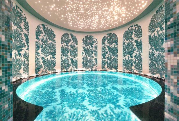 Ein runder Pool mit Mosaiken und einem Deckenlicht, das wie Sterne aussieht.