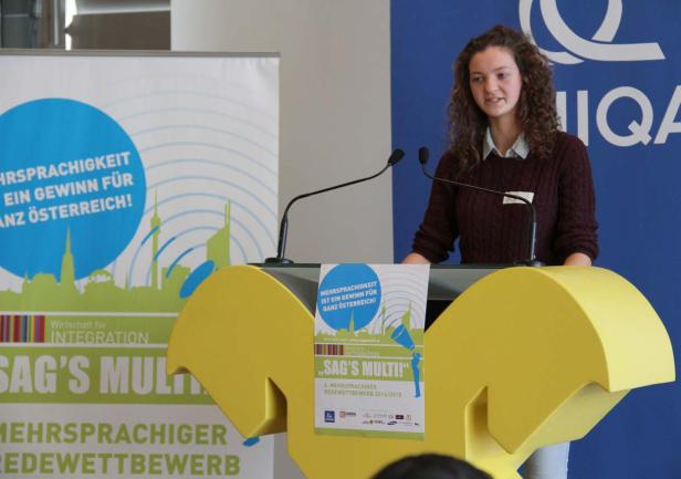 Eine junge Frau hält eine Rede auf einer Veranstaltung zum Thema Mehrsprachigkeit.