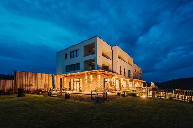 Ein modernes Hotel mit beleuchteter Terrasse in der Abenddämmerung.