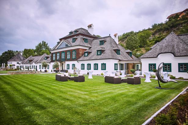 Ein großes, weißes Gebäude mit einem gepflegten Rasen und Gartenmöbeln.