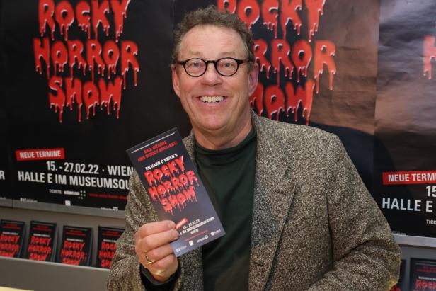 Ein Mann mit Brille hält eine Programmankündigung für die „Rocky Horror Show“ in Wien.