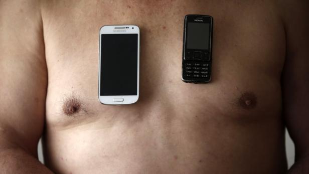 Ein Mann hält ein Samsung-Smartphone und ein Nokia-Handy auf seiner Brust.
