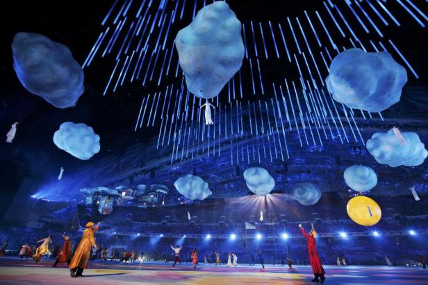 Eine Aufführung mit schwebenden Wolken und Akrobaten in einem Stadion.