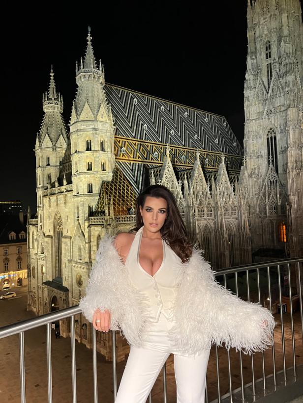 Eine Frau in weißer Kleidung vor dem Stephansdom in Wien bei Nacht.