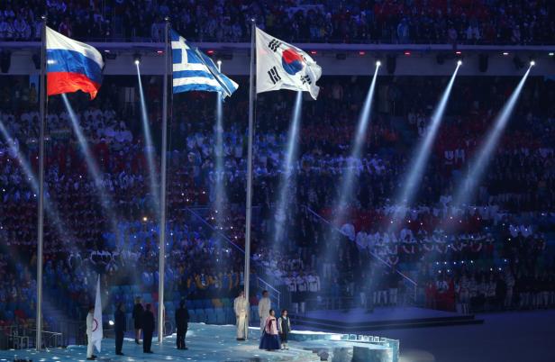 Bei einer Veranstaltung werden die Flaggen von Russland, Griechenland und Südkorea gehisst.