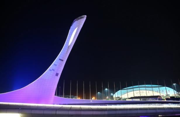 Das Olympiastadion in Sotschi bei Nacht mit dem beleuchteten olympischen Feuer.