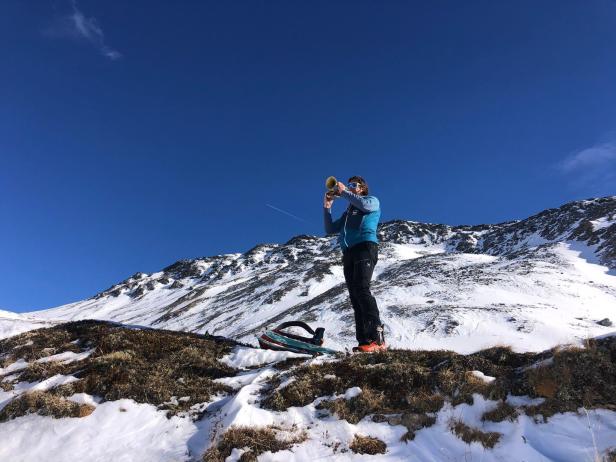 Eine Frau spielt auf einem schneebedeckten Berg Trompete.