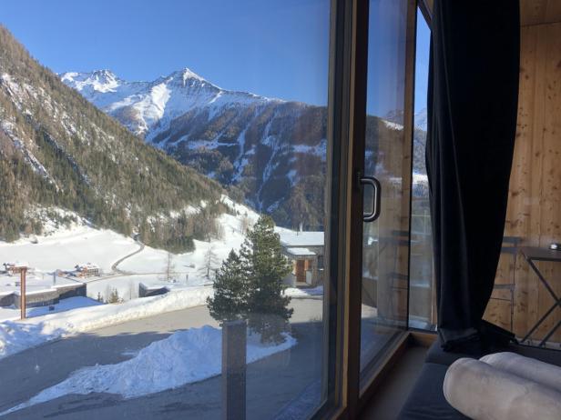 Blick aus einem Fenster auf eine verschneite Berglandschaft.