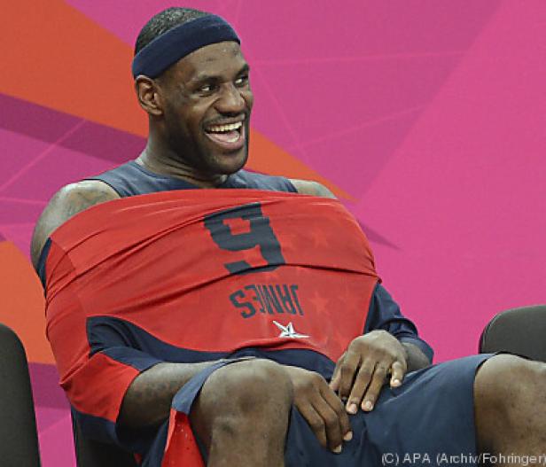LeBron James sitzt lachend mit seinem Trikot um den Hals.