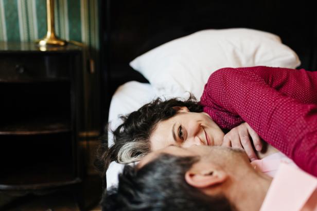 Ein Paar liegt zusammen im Bett und lächelt sich an.