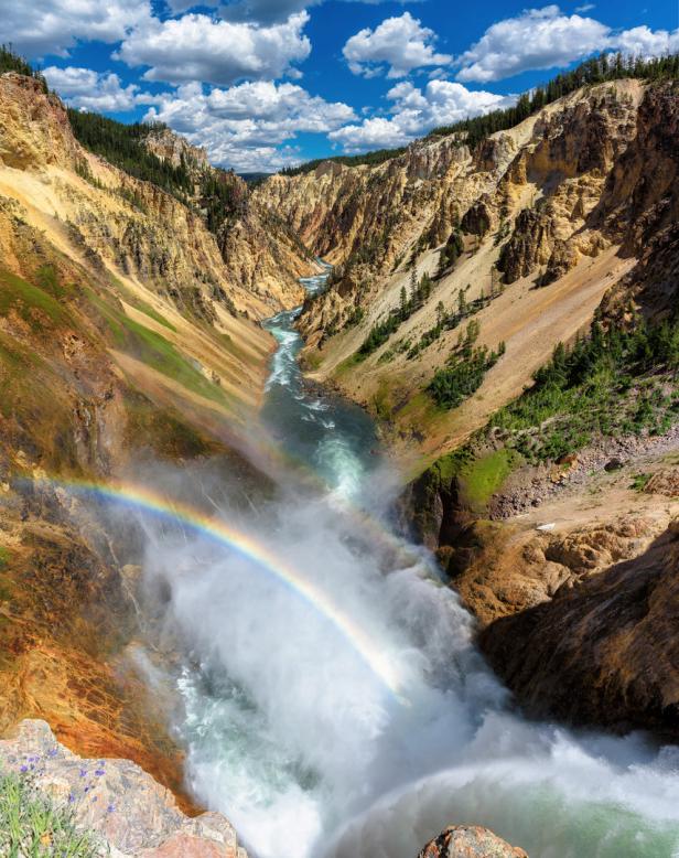 Ein Regenbogen überspannt den tosenden Wasserfall in einer tiefen Schlucht.