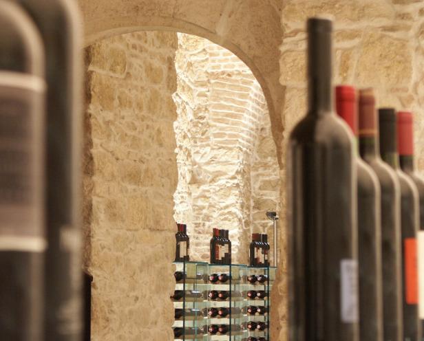 Eine Reihe von Weinflaschen in einem Weinkeller mit Steinwänden.