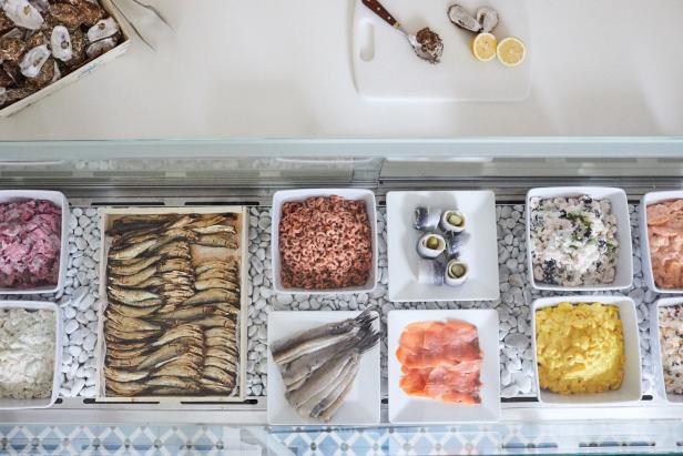 Verschiedene Fisch- und Meeresfrüchtegerichte in einer Auslage, darunter Hering, Lachs und Krabben.