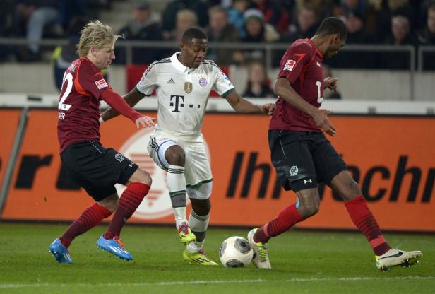 Drei Fußballspieler kämpfen um den Ball auf dem Spielfeld.