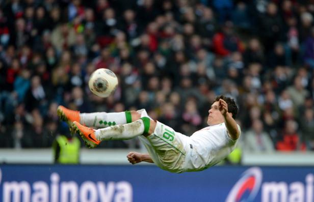 Ein Fußballspieler springt in der Luft, um einen Ball zu treten.