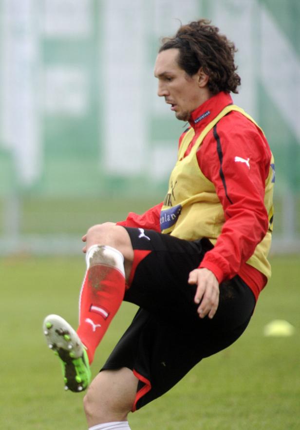 Ein Fußballspieler dehnt sich auf dem Trainingsplatz.
