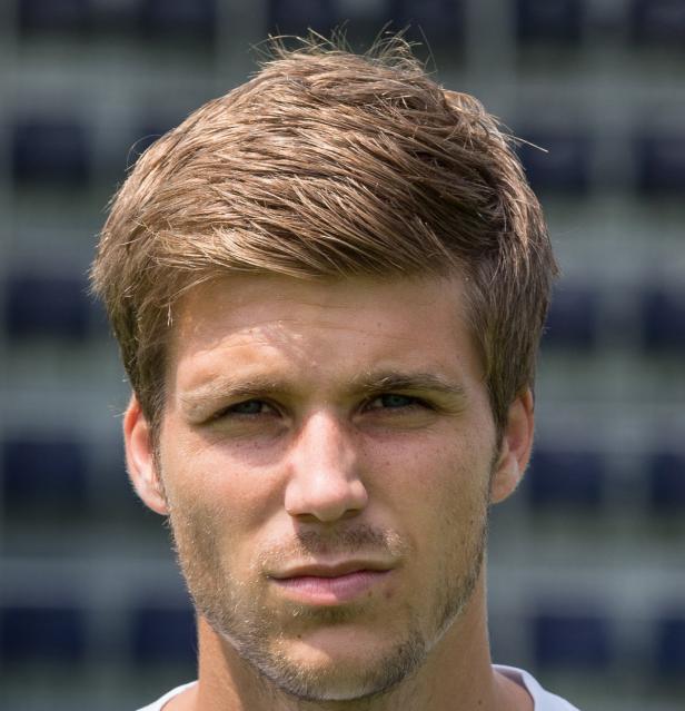 Porträt eines Mannes mit blonden Haaren und ernstem Blick.