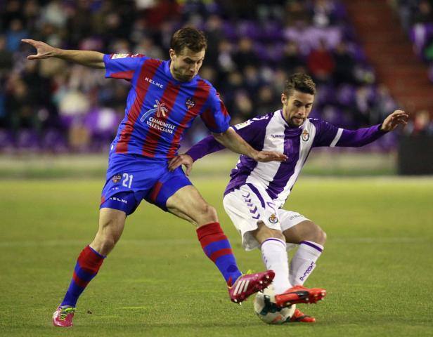 Zwei Fußballspieler kämpfen um den Ball auf dem Spielfeld.